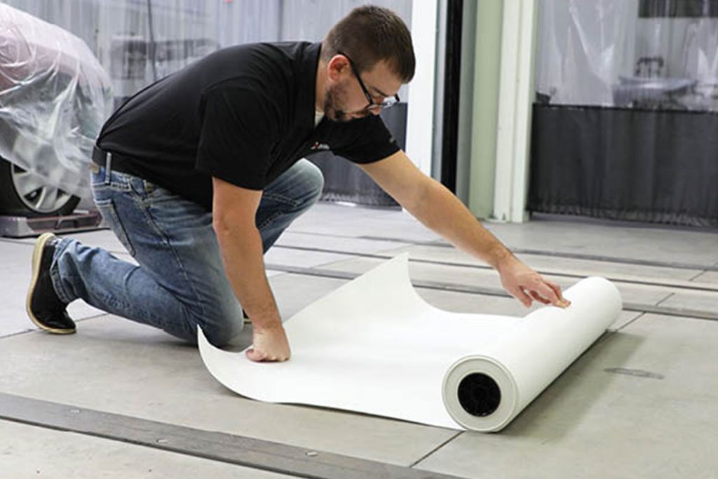 Rolling out paint booth floor protective paper